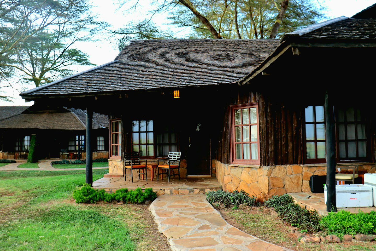 Rustic wooden lodge cabins sit on a green lawn.