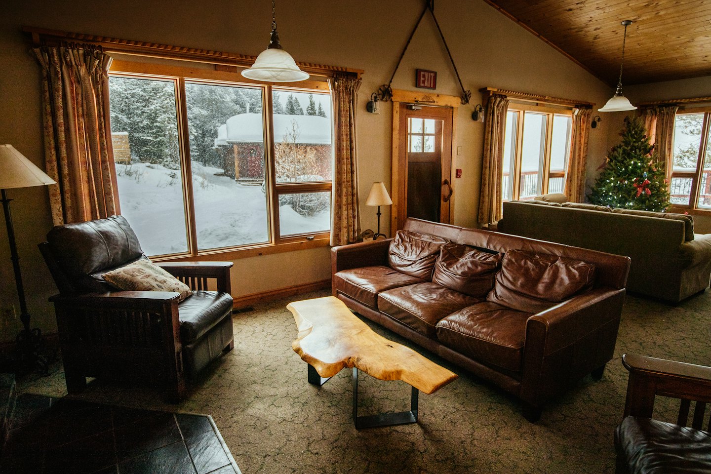 Cozy lodge living room with leather sofa and snowy view.